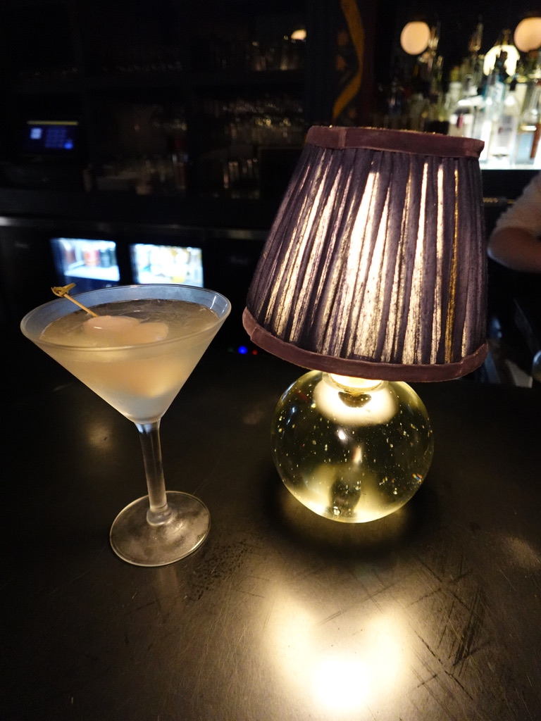 Craft martini glowing under warm lamp light at the bar