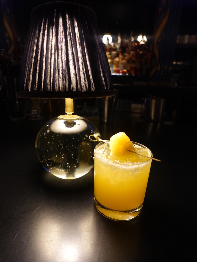 Orange-hued cocktail lit by a table lamp