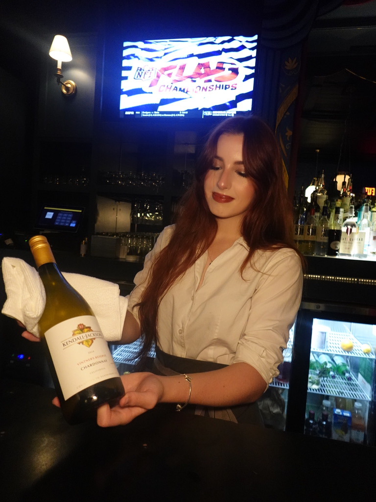 A server presenting a bottle of wine at Estelle's Oxford