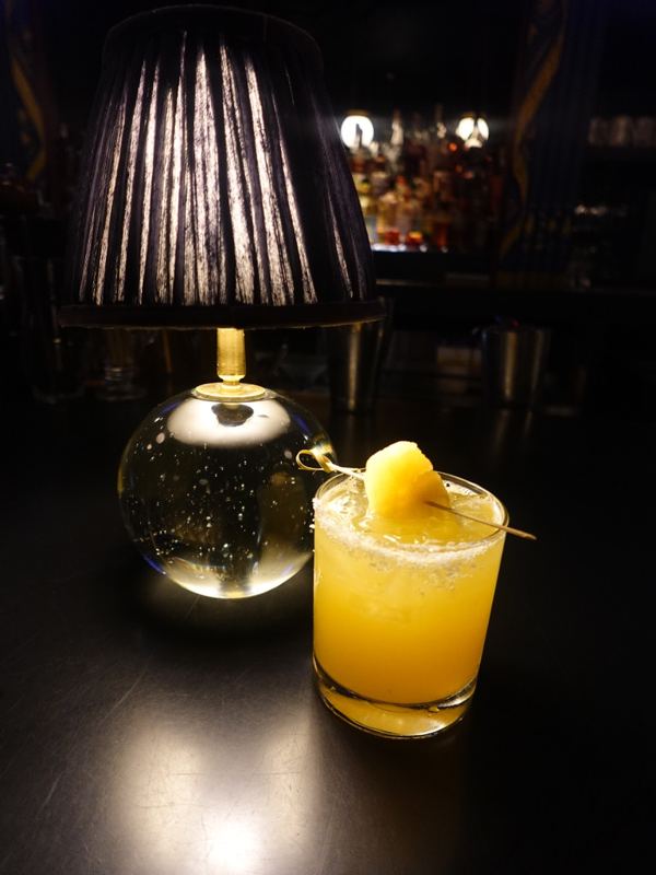 Orange-hued cocktail lit by a table lamp